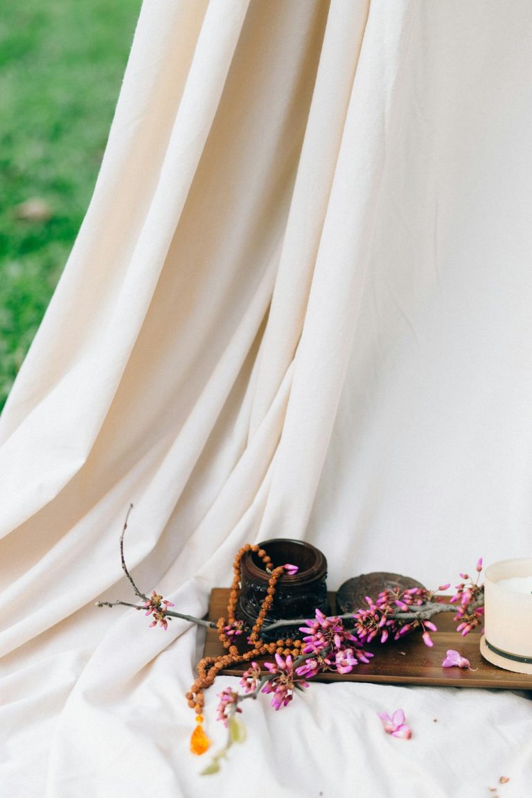Serene still life of flowers on wood with flowing drapery outdoors.